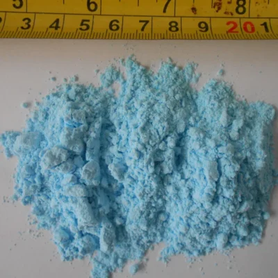 Blue powder granules with a measuring tape for size reference